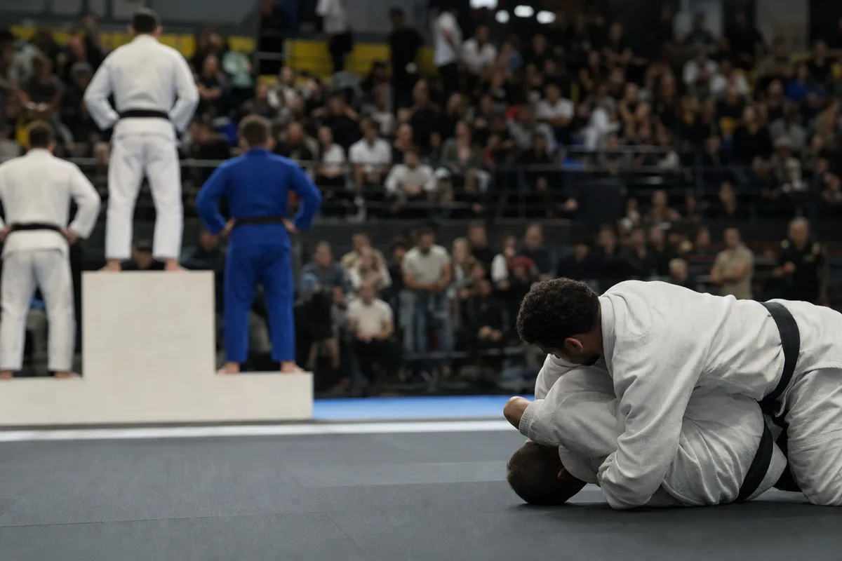 Compétition moderne de jiu-jitsu avec podium, athlètes en kimono et public dans les gradins
